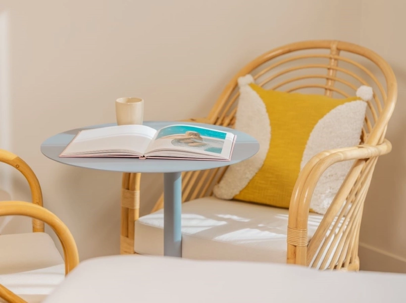 Détail de la chambre familiale du Nice Pam Hotel à Nice avec fauteuil en rotin, coussin jaune et table d’appoint